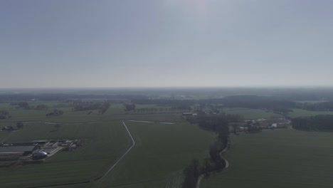 Langsam-Von-Oben-Nach-Unten-Geschossene-Drohnenaufnahme-Einer-Bauernstadt-Mit-Nebenstraße-Und-Einer-Baumgrenze