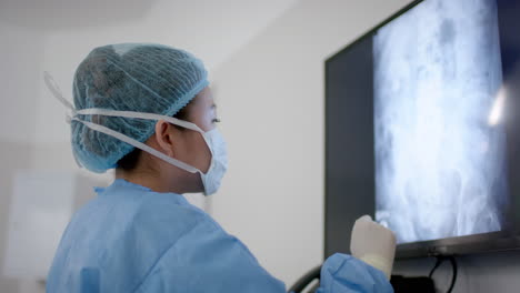 asian female surgeon looking at x-ray scans in operating theatre, slow motion