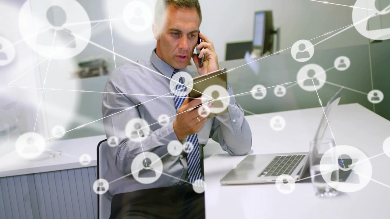 Exec holding phone and using tablet, initiating network overlay showing business links over laptop