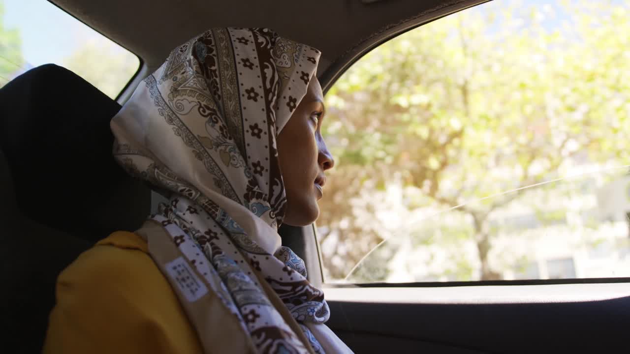 mujer joven con hijab sentada en un taxi conduciendo en una ciudad