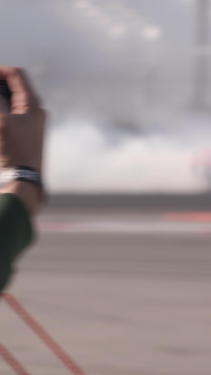 Person Recording a Racing Event with a Mobile Phone