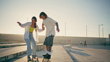 happy pair riding skate boards sunny stadium. carefree couple enjoying summer