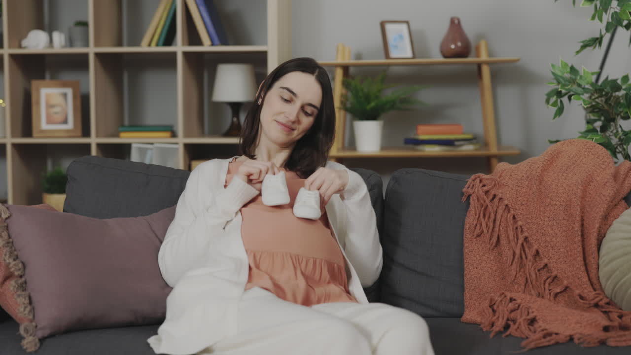 Pregnant woman looking at baby shoes