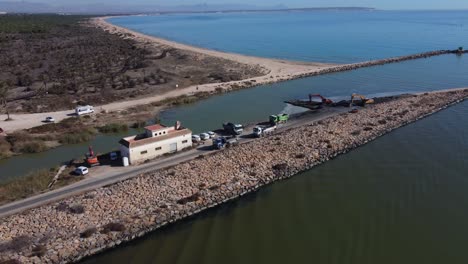 Aerial-revealing-heavy-machinery-removing-mud-and-sludge-on-a-river-mouth