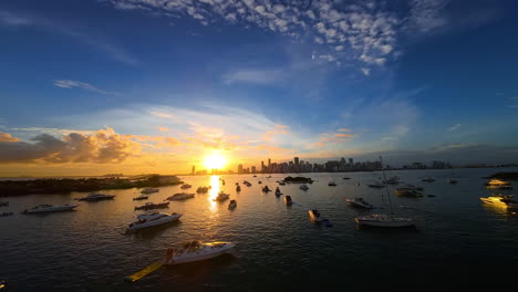 fpv drone flying above the waterscape with multiple boat on surface. american metropolis skyline at sunset at backdrop.