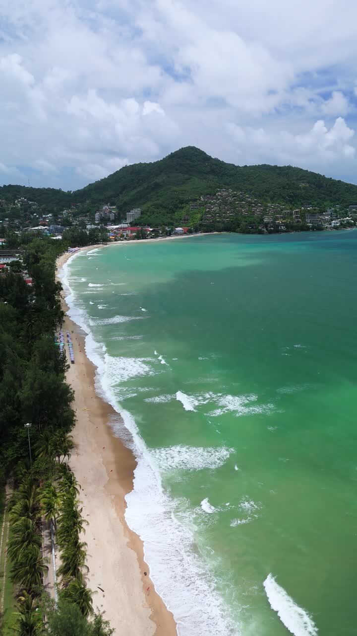 Vertical aerial ascend reveals Kamala Beach shoreline and surf, Phuket