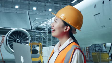 female engineer with laptop in airplane hangar