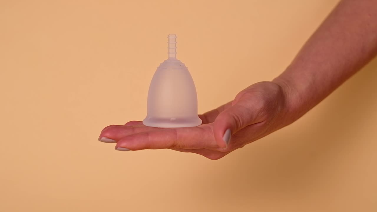 Mãos de mulher segurando um copo menstrual ecológico