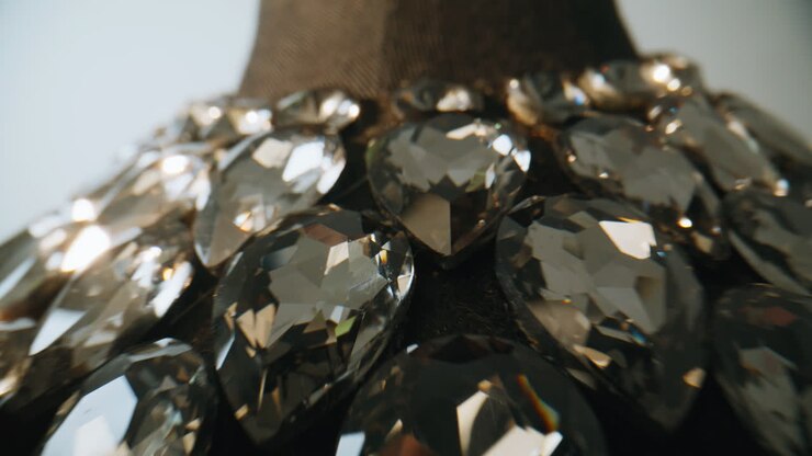Collana con pietre preziose disposta su un busto in tessuto in una stanza tranquilla. Oggetto di gioielleria