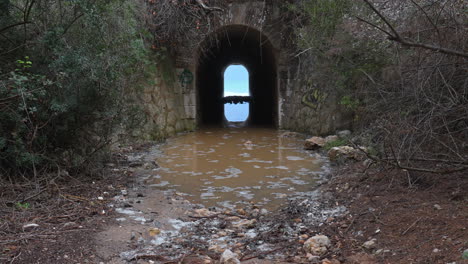 a tunnel leads towards a wild sea, where incoming waves create a rippling effect