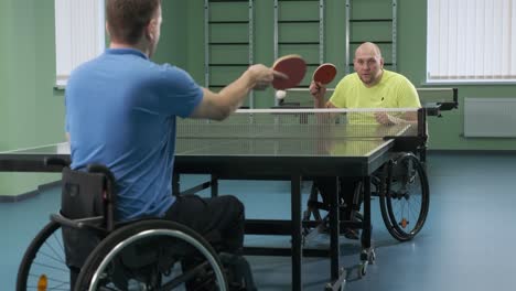 un hombre en silla de ruedas juega al ping-pong. personas con discapacidad juegan al tenis de mesa. rehabilitación de discapacitados. deporte.