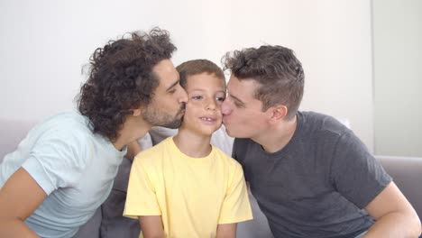 dos padres felices besando a su hijo