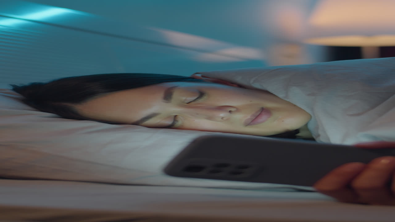 Woman Lying in Bed at Night and Using Phone