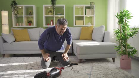 old man cleaning at home, using vacuum cleaner to clean carpet and floor in living room.
