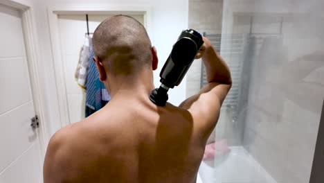 a man using a massage gun for relaxation in a contemporary bathroom environment. slow motion