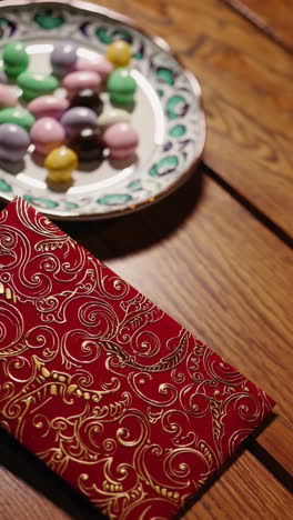 colorful candies and red envelope on wooden table
