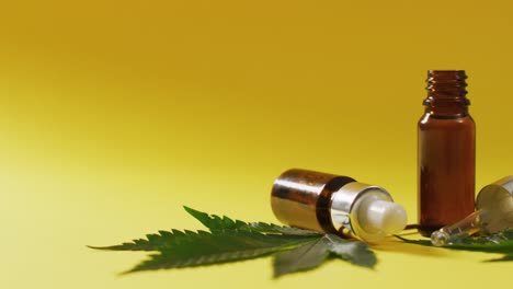 Video-of-marijuana-leaves-and-bottle-of-cbd-extract-on-yellow-background