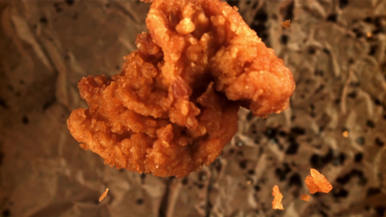 Tira de pollo frito dorada sobre papel marrón arrugado.