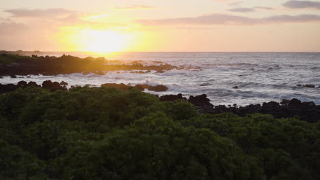 Serene-sunset-at-rocky-beach-with-calm-waves-reaching-shore