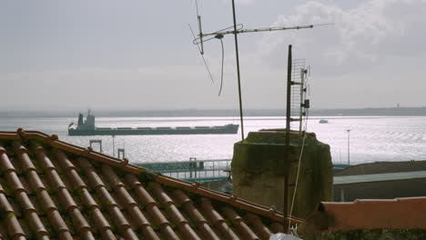 an enormous container ship sits anchored off portugal’s capital, lisbon