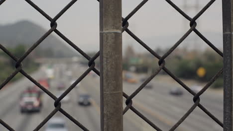 an overpass fence towards a busy highway on an overcast day.