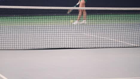 Tennis-player-behind-net-on-court,-serving