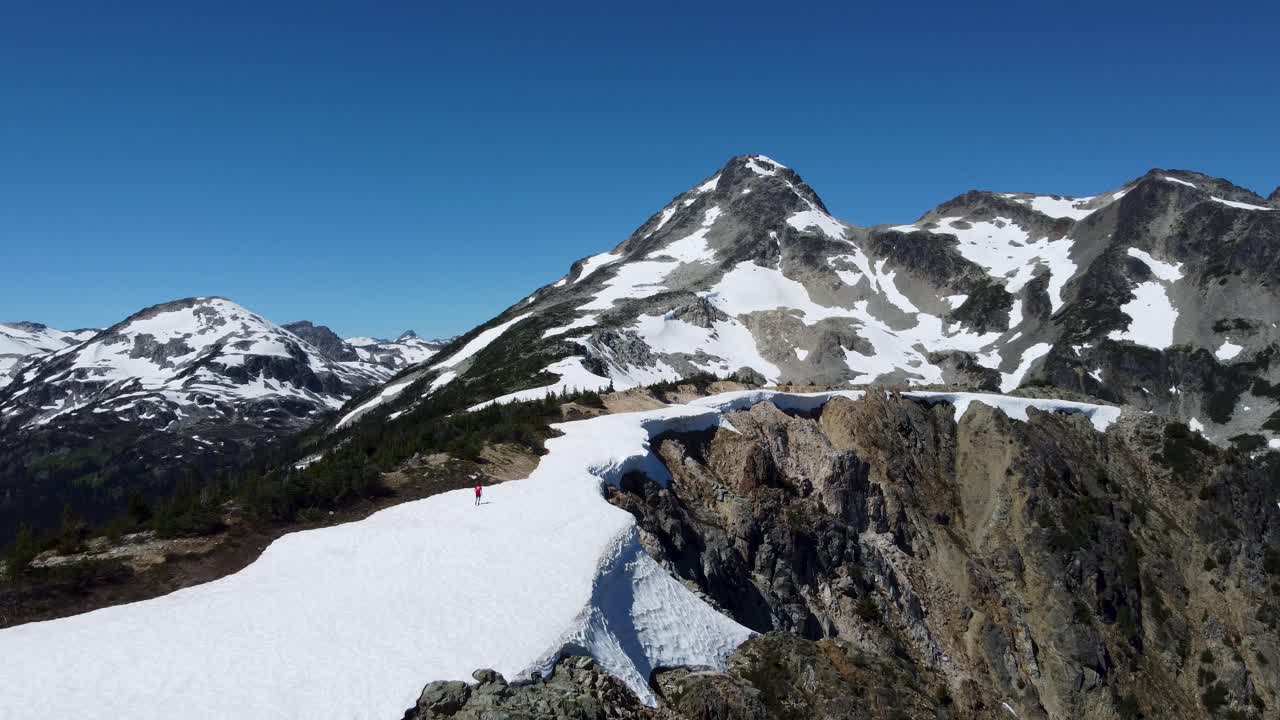 persona caminando a través del paisaje montañoso cubierto de nieve con acantilados escarpados
