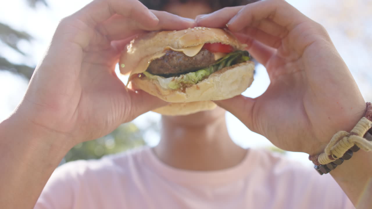 Holding burger, man preparing to take bite during outdoor hangout
