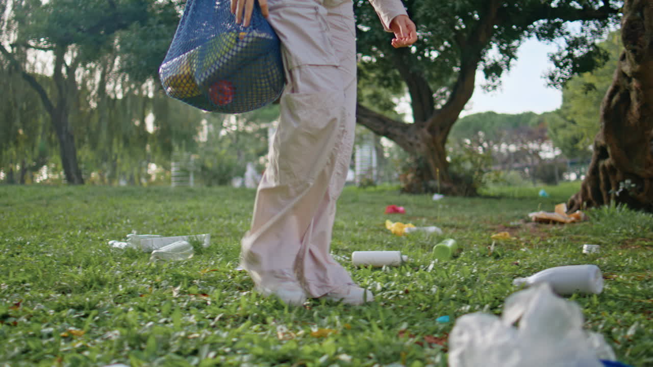voluntario caminando por el parque, basura, contaminación. niña conservacionista pisando el césped.