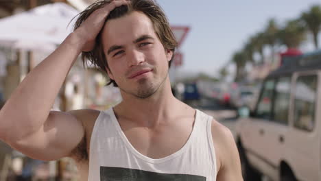 portrait of attractive young man running hand through hair smiling confident