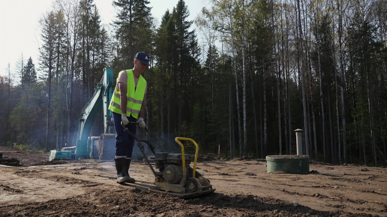 Man operating a vibratory plate compactor on a construction site