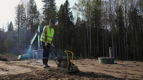 man operating a vibratory plate compactor on a construction site