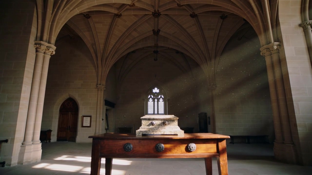Shifting sunlight entering right arched window sliding across chapel table with tomb, showing knobs
