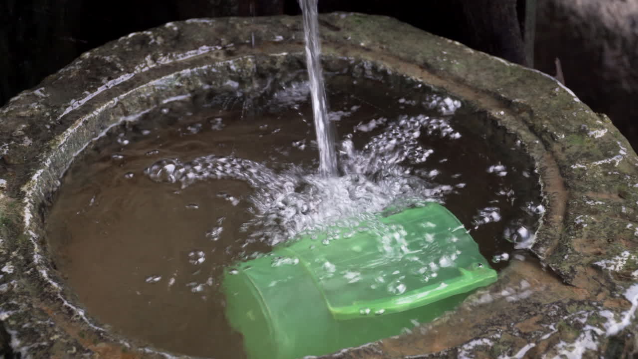 녹색 플라스틱 주전자가 떠 있는 수영장으로 떨어지는 물줄기