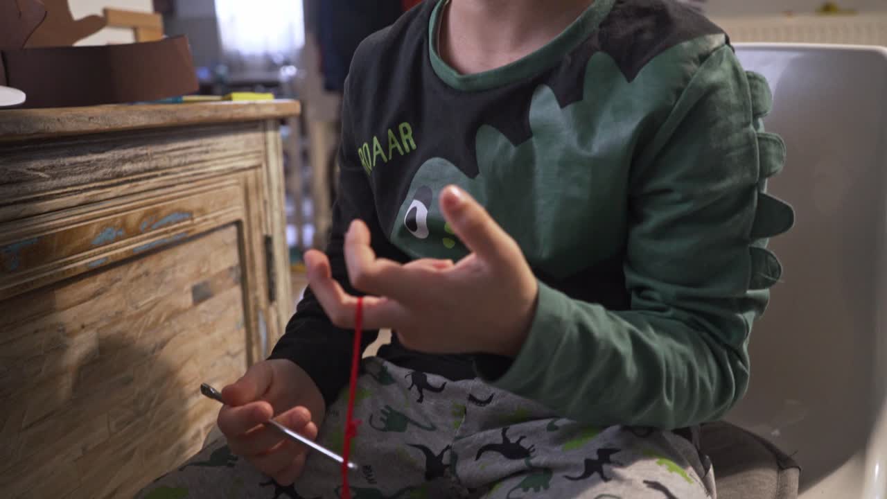 primer plano inclinado de un niño caucásico, sosteniendo cascabeles y viendo la clase de escuela a distancia en casa, durante el bloqueo del coronavirus