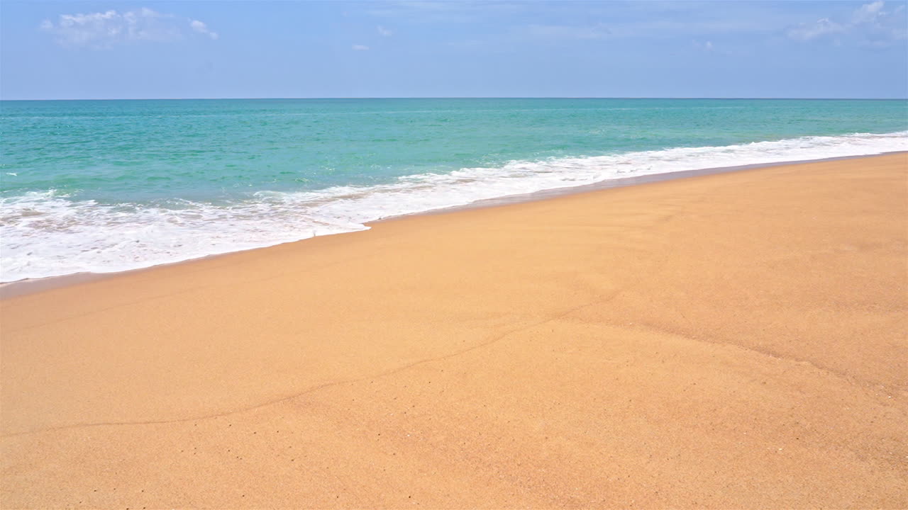깨끗한 해변의 황금빛 모래 위로 밀려오는 파도의 슬로우 모션