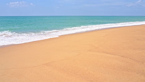 slow-motion of ocean waves washing up over the golden sand of a pristine beach