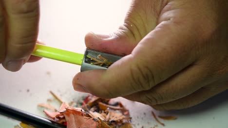 footage of hands slowly sharpening a pencil and some coloured pencils with a wedge pencil sharpener