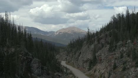 aerial dolly of creek and road with mountain peak in background in colorado