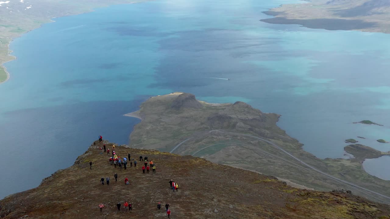reyðarfjörður 피요르드가 보이는 홀마틴두르 산 가장자리 근처에 서있는 사람들