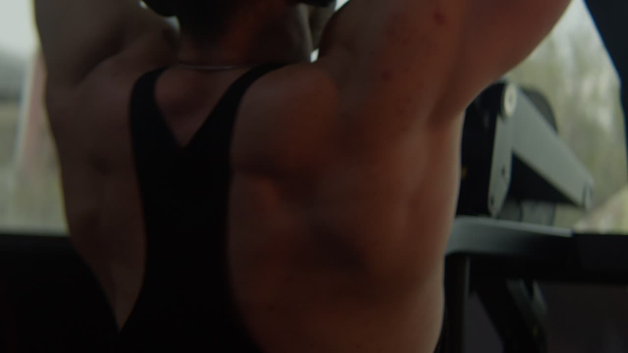 athlete walking towards back Workout machine to shape up his back,  handheld close up shot