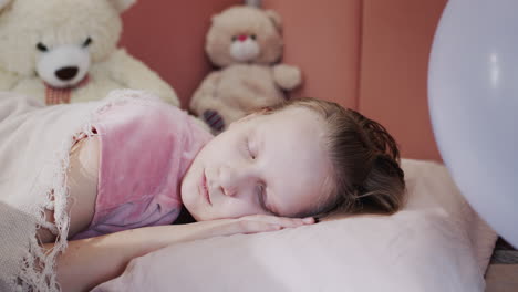 Portrait-of-a-girl-sleeping-in-her-bed,-in-the-background-of-her-toys