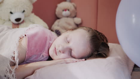 retrato de una niña durmiendo en su cama, en el fondo de sus juguetes