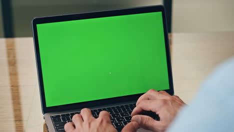 manos de hombre escribiendo chromakey portátil en el lugar de trabajo closeup. jefe presionando botones