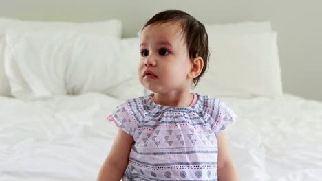 Cute-baby-girl-sitting-on-bed