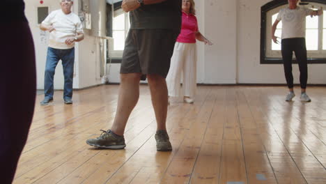 senior people having dance class with teacher in ballroom