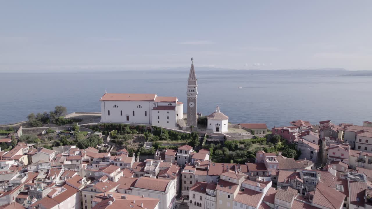Video with drone from overhead shot backwards over the city of Piran in Slovenia, starting with the Church as the main one and ending from overhead at the marina passing through the central square