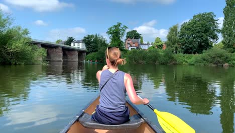 girl paddling canoe on river wye on sunny day with blue skies