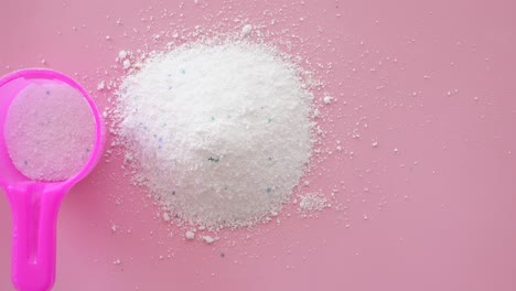 primer plano de polvo de detergente para la ropa y una cuchara rosada