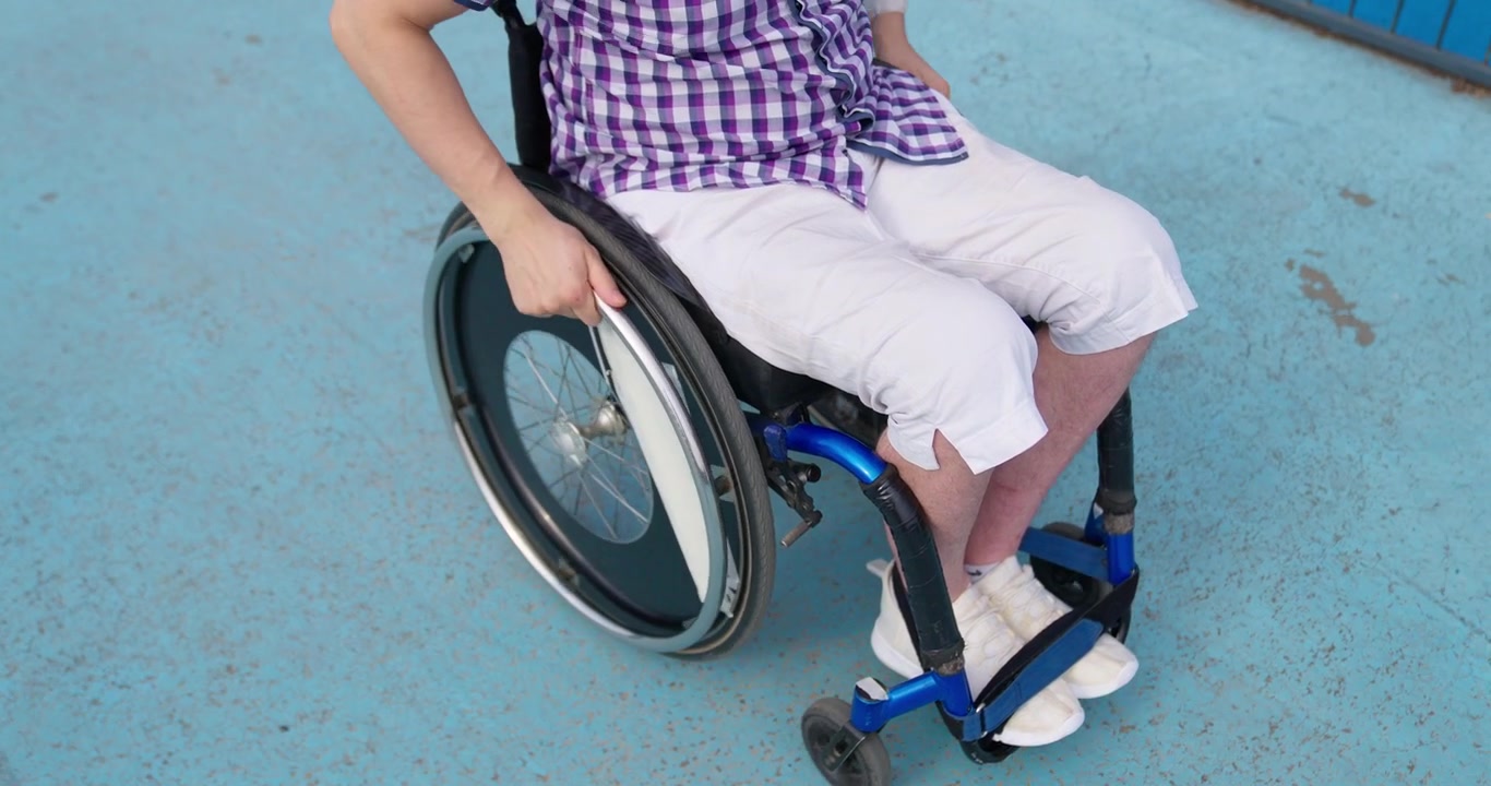 Close-up of a Person in a Wheelchair Pushing the Wheel Outdoors